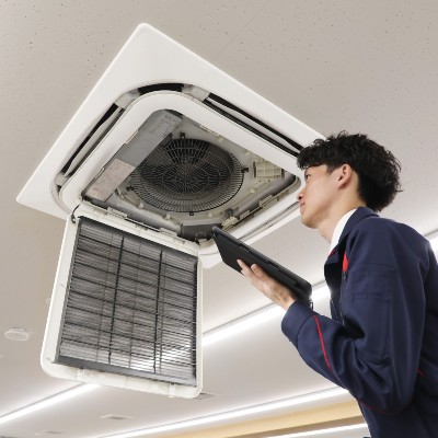 業務用の天井にある空調を確認している男性